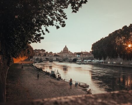 A beautiful shot of a black concrete pathway beside the body of waterin Rome, Italy during sunset